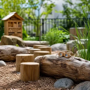 Outdoor nature play space with logs, climbing elements, and discovery activities that support healthy childhood development.